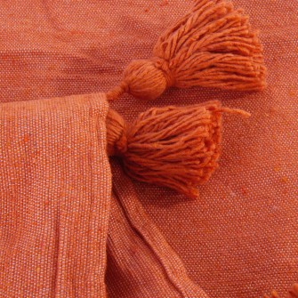 Ceglasty pled bawełniany. Ręcznie tkana, kwadratowa narzuta w kolorze pomarańczowym z chwostami. Ciepły akcent do wnętrz w stylu boho.