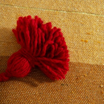 Wielokolorowy pled bawełniany w pasy. Ręcznie tkana narzuta z czerwonymi chwostami. Energetyczny dodatek w stylu boho i etno.